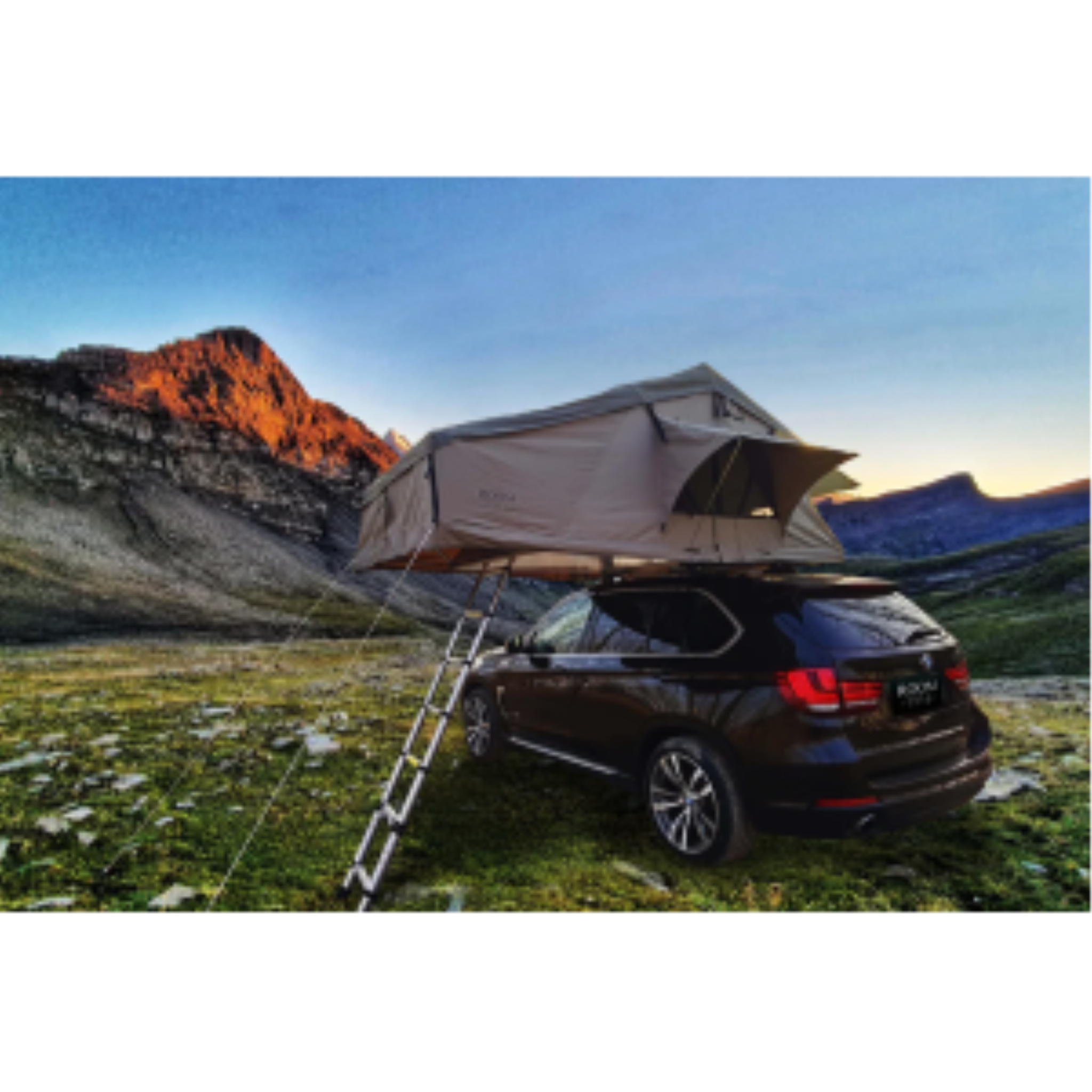 K&B Sport Deluxe rooftop tent on a dark SUV parked in a mountain valley during sunset.