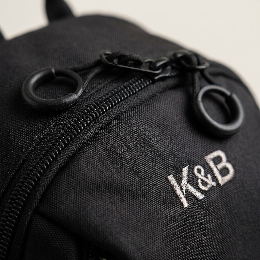 Close-up of the Bugatti Mini Adventure Backpack showing metal ring zipper pulls and K&B embroidery.